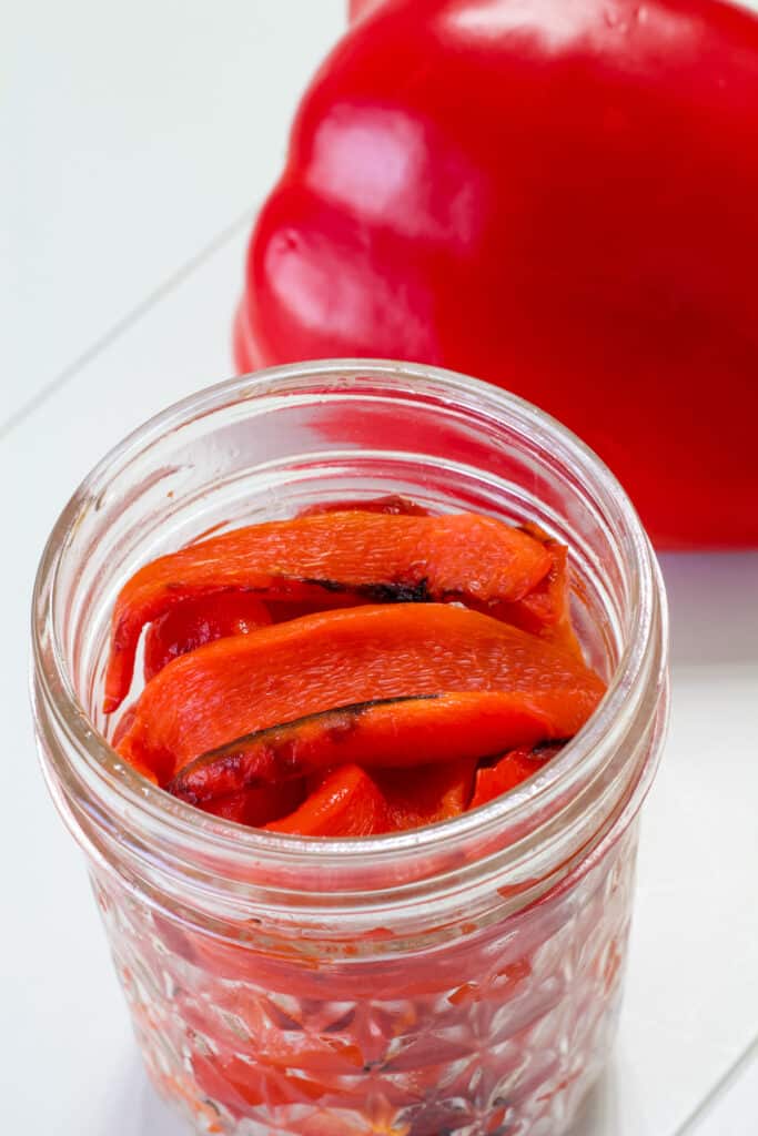 Roasted red pepper strips in a small mason jar without the lid.