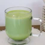 One clear glass coffee cup full of hot matcha tea latte.