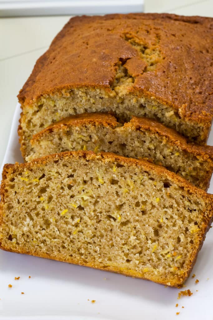 A cut loaf of Yellow Summer Squash Bread on a white plate so the inside of the bread is visible.
