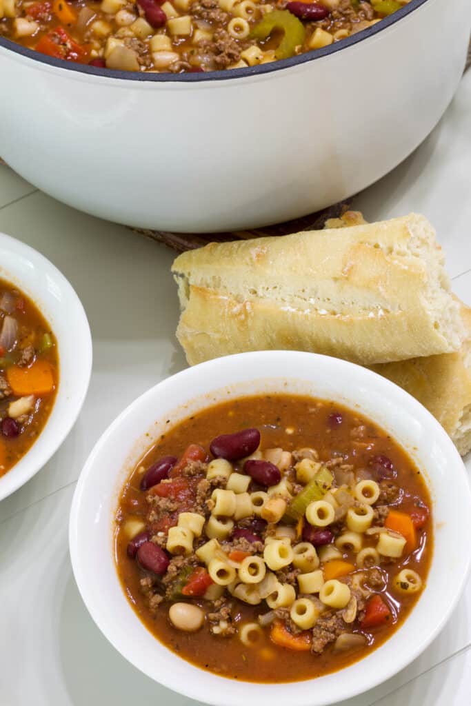A bowl of olive garden’s pasta e fagioli soup and a couple of pieces of crusty bread.