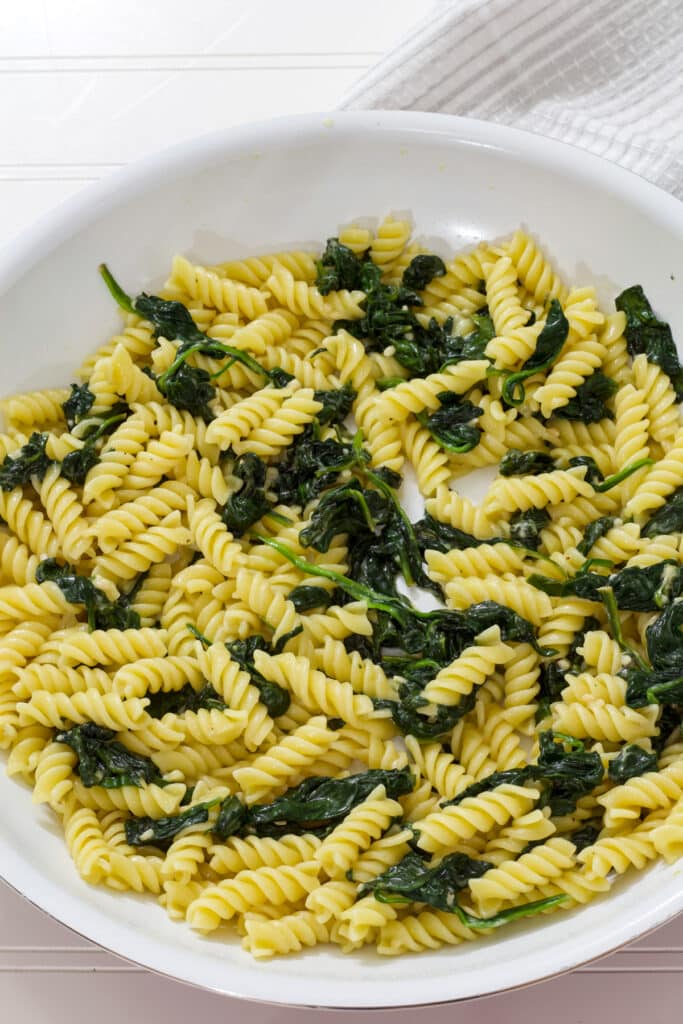 A large skillet filled with the finished Easy Garlic Butter Pasta and Sautéed Spinach.