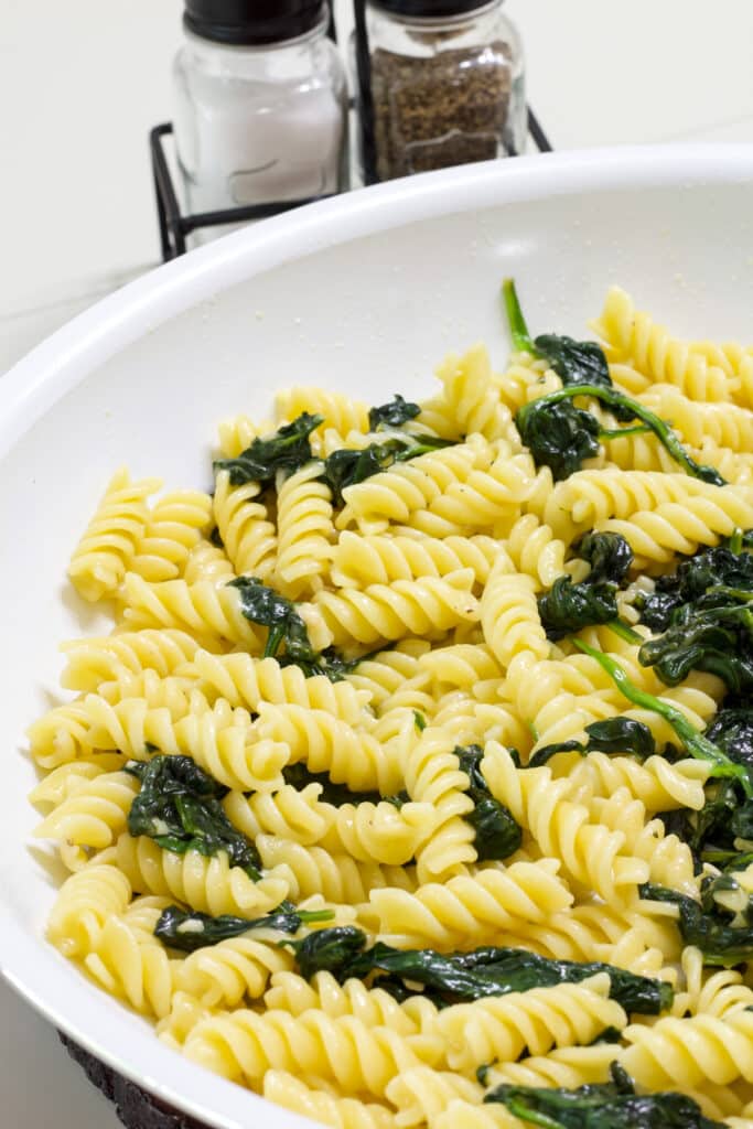 Half of the skillet with Easy Garlic Butter Pasta and Sautéed Spinach in it.