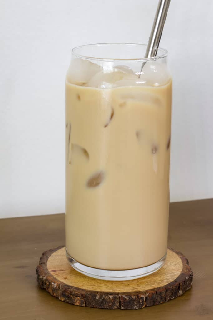 A tall glass with one serving of Easy Homemade Starbucks Iced Vanilla Coffee in it, there is a silver straw sticking out of the glass.