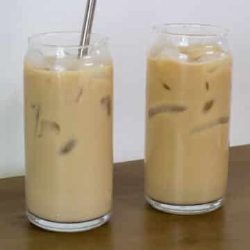Two glasses of Easy Homemade Starbucks Iced Vanilla Coffee, one with a straw and one without.