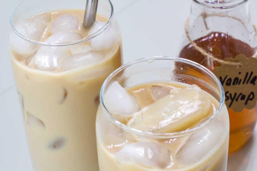 Overhead view of two glasses of iced coffee and the bottle of homemade vanilla syrup behind one of the glasses.