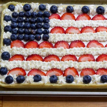 The left half of the uncut patriotic dessert pizza so the white stripes and red stripes are visible.