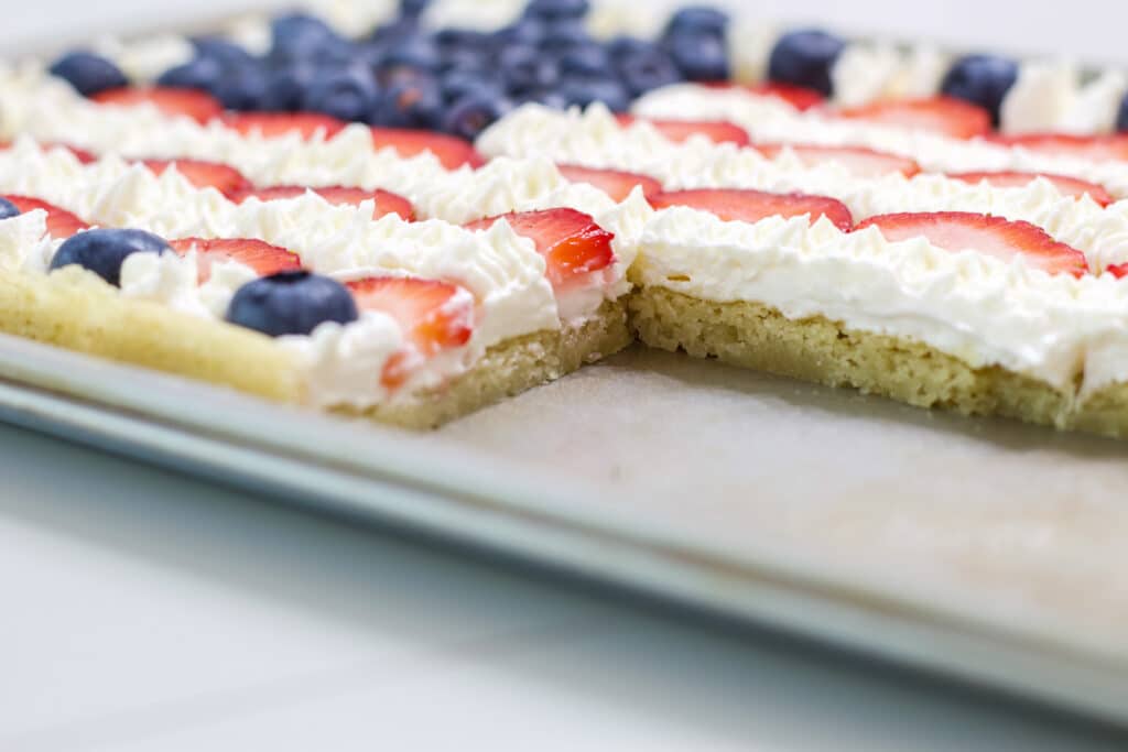 The cut July 4th Flag Patriotic Fruit Pizza in the pan so the inside of the sugar cookie crust is visible.