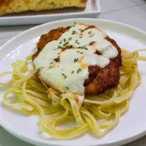 One piece of crispy chicken Parmesan on a bed of fettucini.