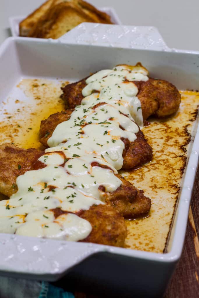 Four cooked chicken filets in the casserole dish.