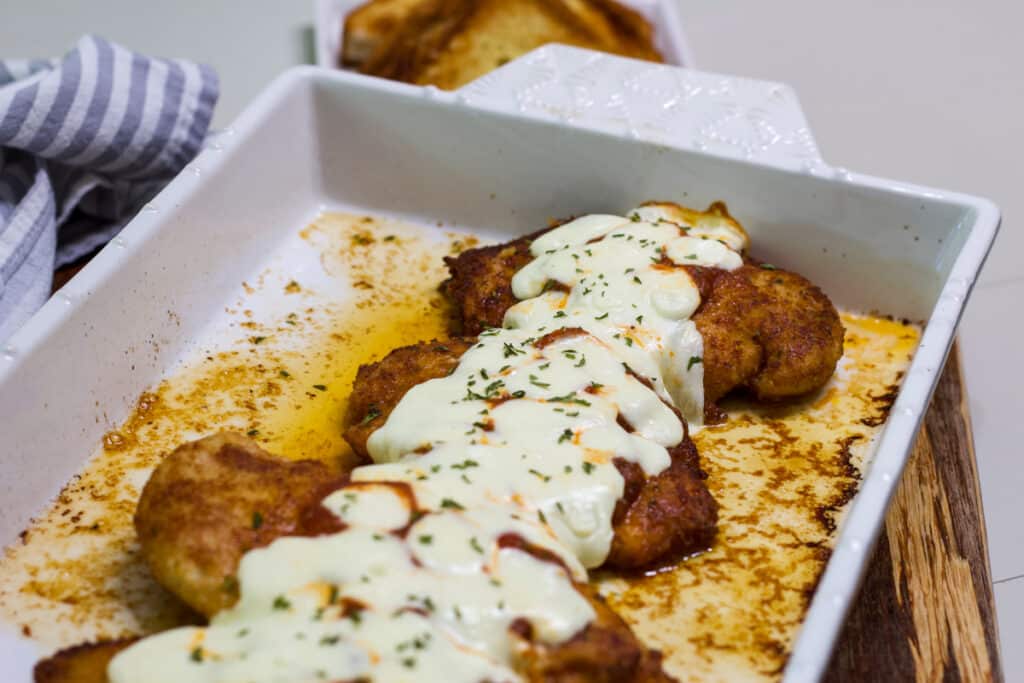 Half of a pan of Crispy Chicken Parmesan, there is melty mozzarella cheese on top.