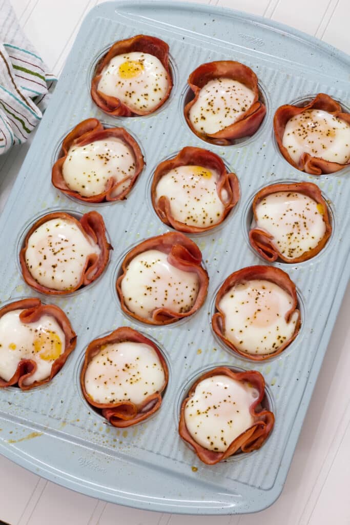 A turquoise twelve cup muffin tin filled with Baked Ham Cheese & Egg Breakfast Cups.