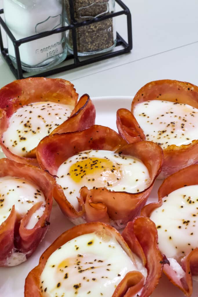 Several oven Baked Ham Cheese & Egg Breakfast Cups on a white plate.