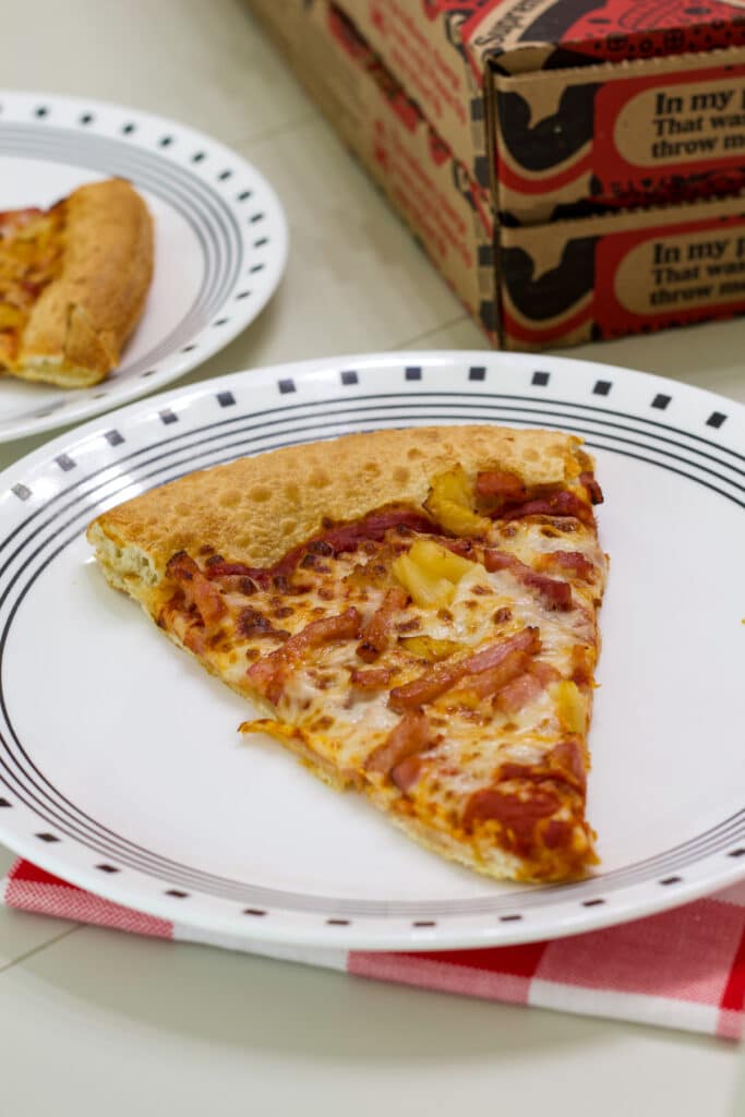 A slice of pizza on a plate after it has been reheated in the air fryer.