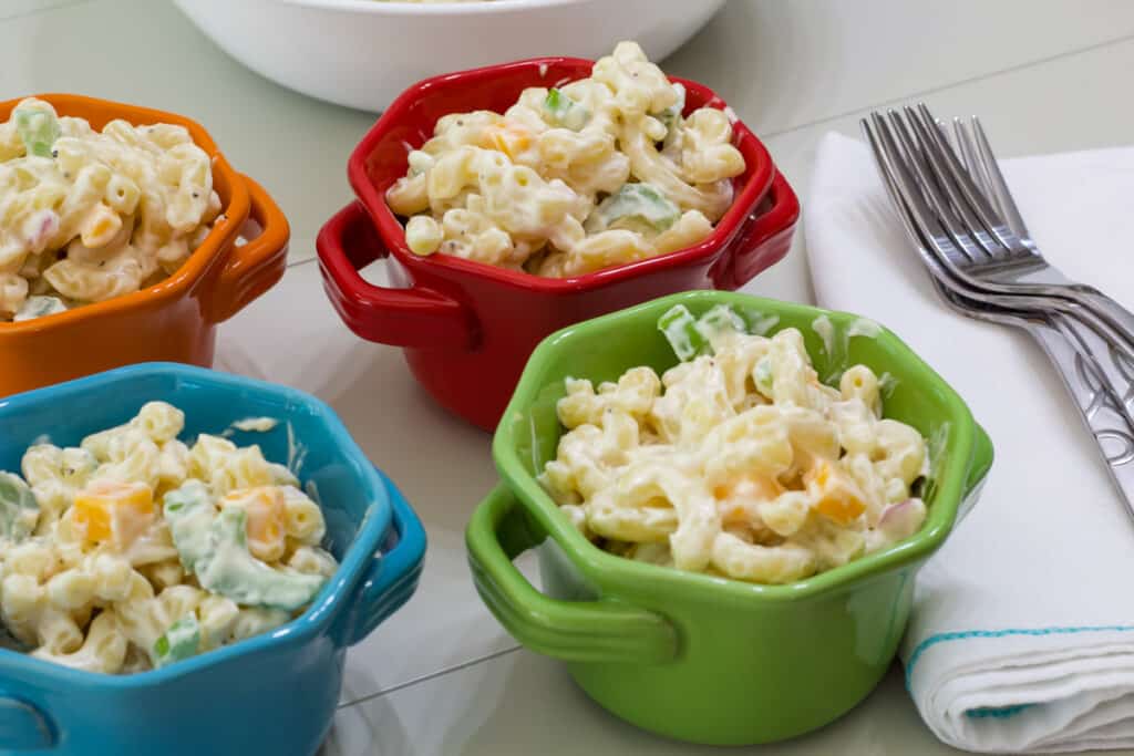Four small bowl filled with creamy macaroni salad.