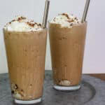 Two glasses of mocha frappuccino sitting on an aluminum looking platter.