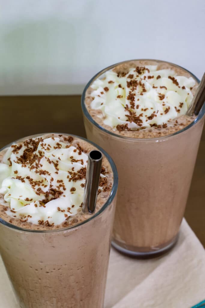 Overhead view of 2 glasses of mocha frappuccino with silver straws in them.