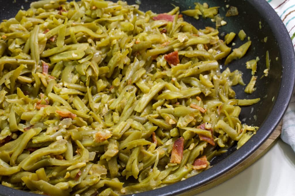 A large skillet with all of the maple dijon green beans in it, they have not yet been topped with Parmesan cheese.