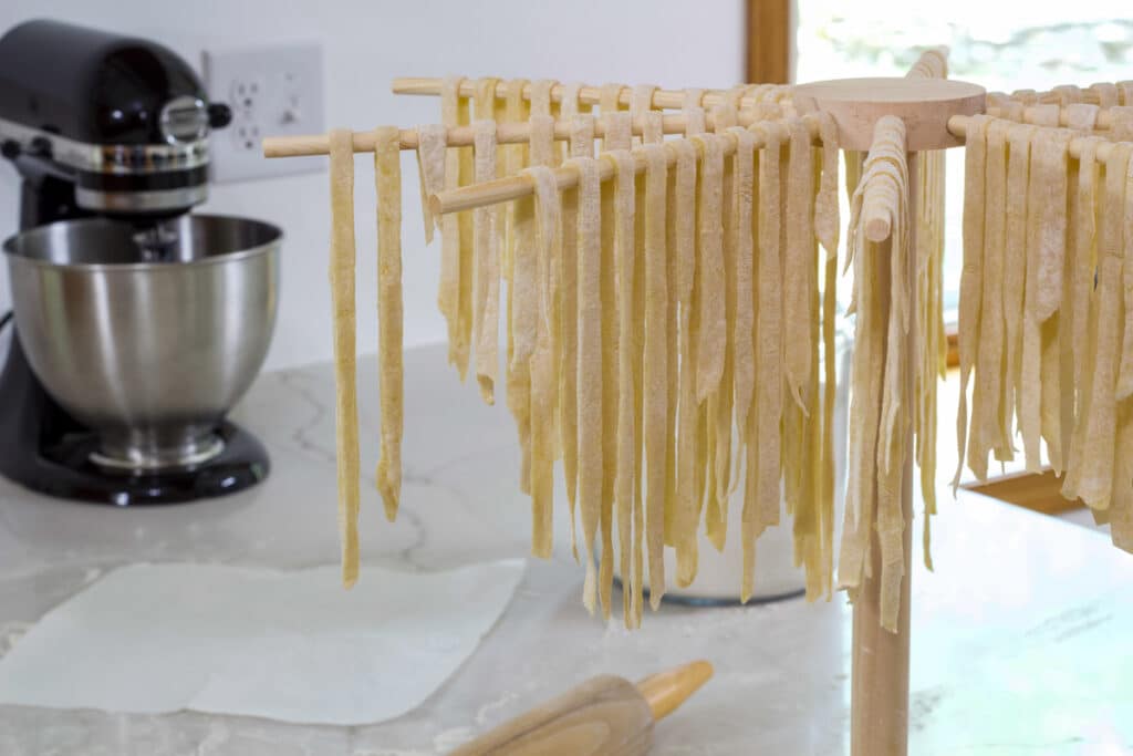 Homemade Egg Noodles Pasta Recipe (like Reames) hanging on a wooden drying rack.