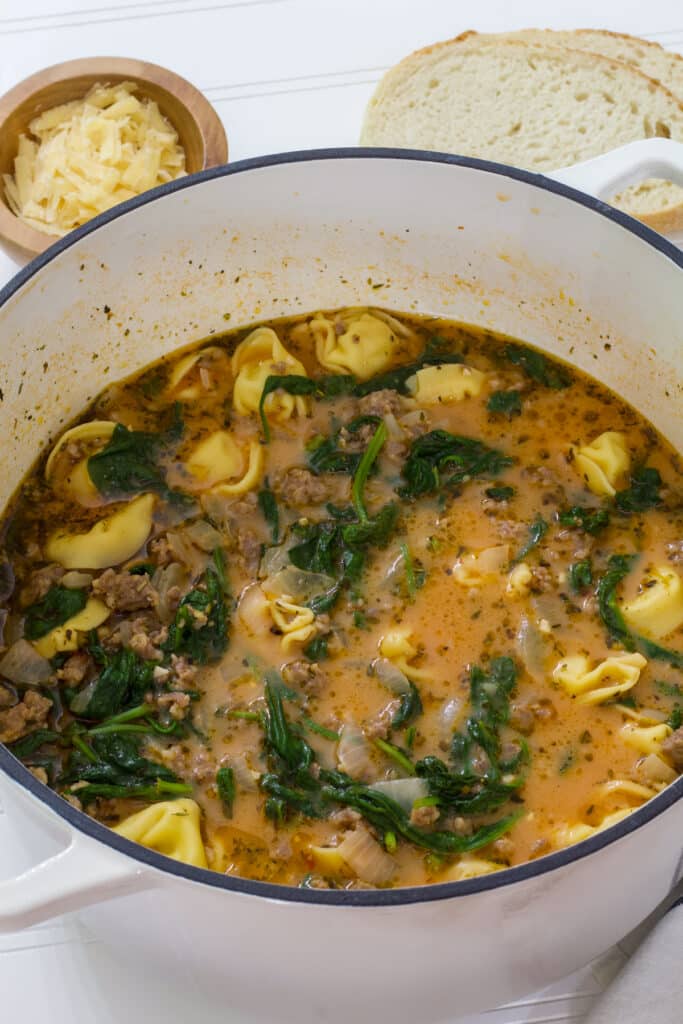 A large white pot full of Rustic Italian Tortellini Soup with Sausage.