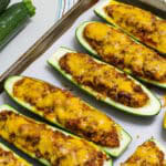 Feature image of several cooked zucchini halves on a parchment paper lined baking sheet.