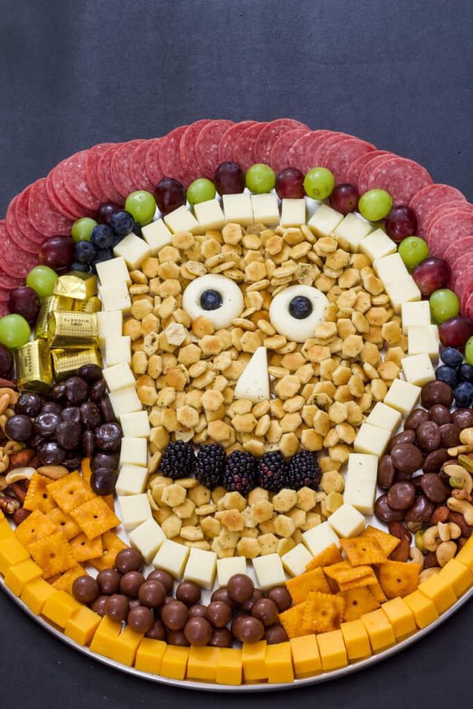 Close up view of the halloween snack board with a variety of meats, cheeses, crackers, fruit and candy.