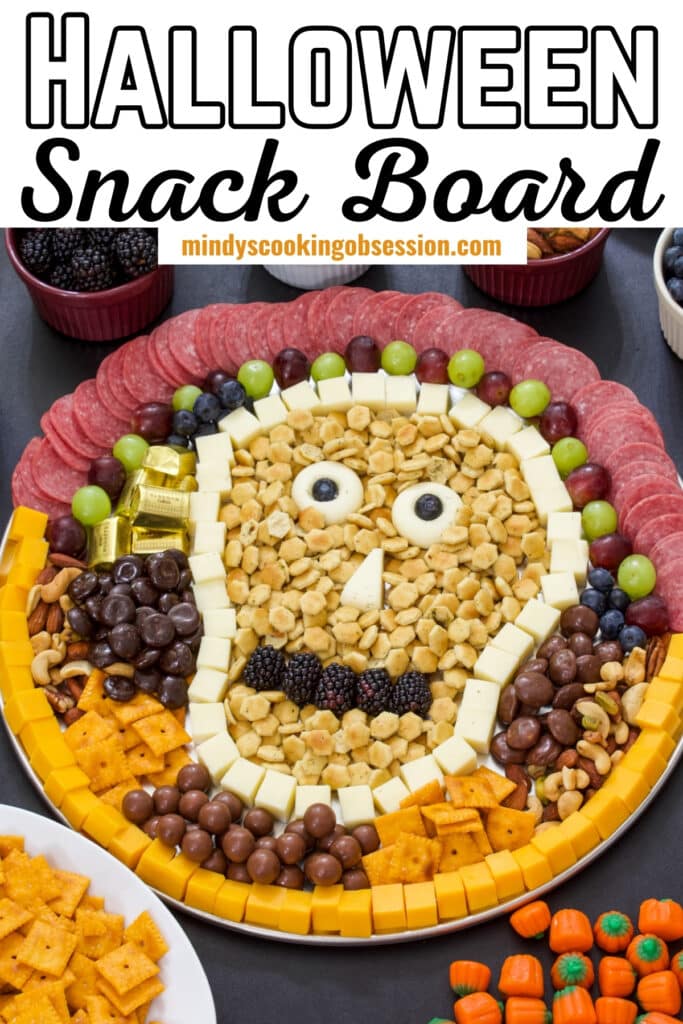 A Halloween charcuterie board in with a skull shape, the recipe title is at the top in text so it can be pinned on Pinterest.