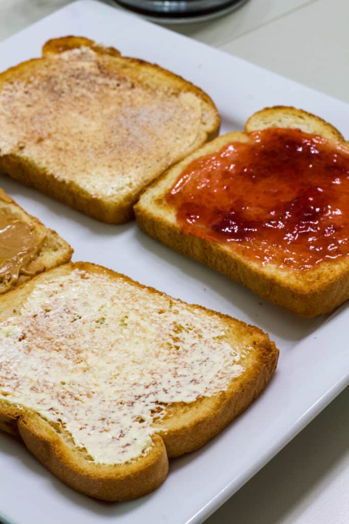 Four pieces of air fried toast that have been topped with different things, butter, peanut butter, jelly, and cinnamon sugar.