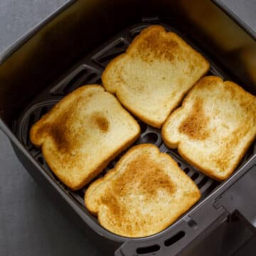 Feature image of 4 slices of toasted white bread in the air fryer basket.