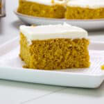 Feature image of one pumpkin cake bar on a white square plate.