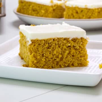 Feature image of one pumpkin cake bar on a white square plate.