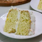 Feature image of one piece of Peach Cake topped with Canned Peaches and Cool Whip on a white plate.