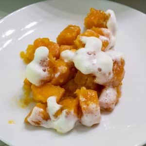 Feature image of one serving of Sweet Potatoes Topped with Marshmallows on a white plate.