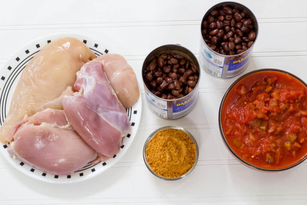 The raw chicken, black beans in the cans, a bowl of salsa and a small bowl of taco seasoning to make the Crockpot Mexican Chicken (easy slow cooker recipe).