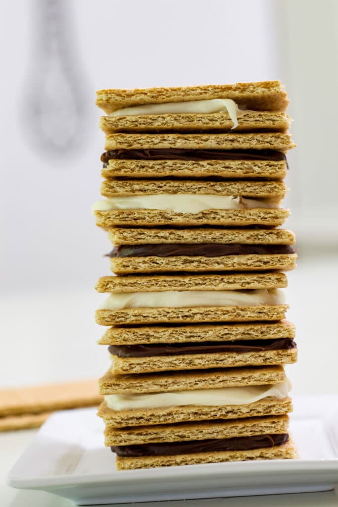 A stack of graham cracker and frosting cookies that alternate between chocolate and cream cheese frosting.