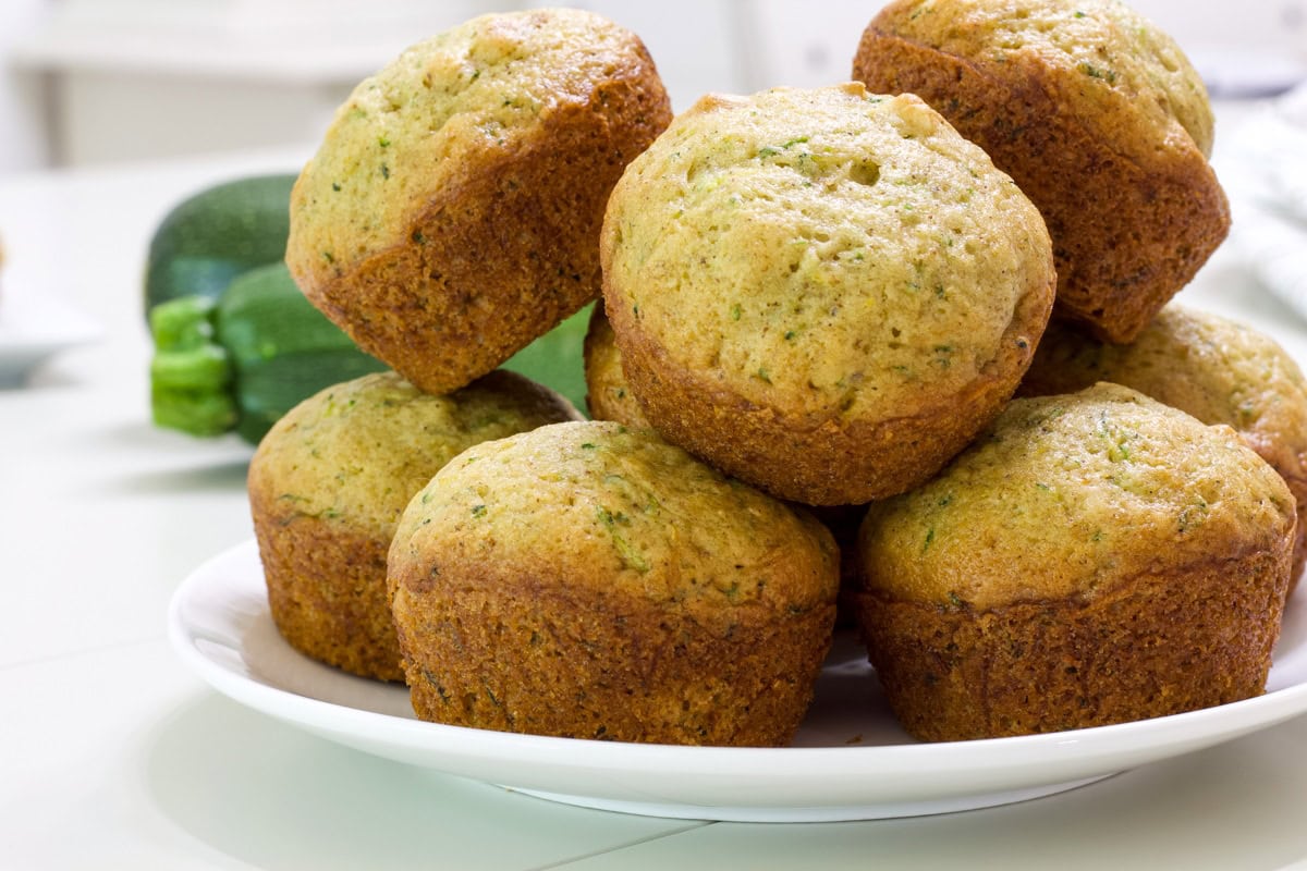 Several zucchini muffins stacked on a white plate.