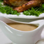 Feature image of a white gravy boat filled with homemade giblet gravy.
