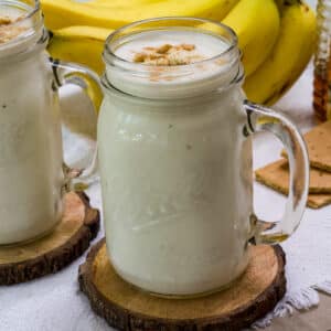 Feature image of a one banana smoothie in full view on a round wooden coaster.