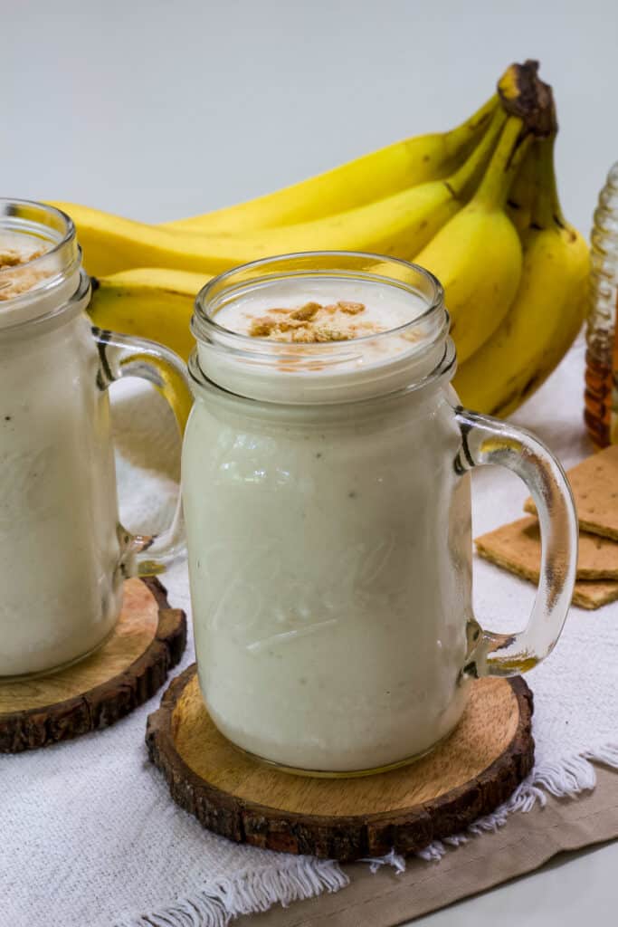One smoothie with a bunch of bananas in the background.