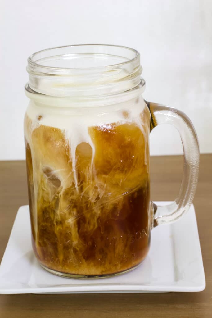One mason jar mug full of vanilla cold brew, the white cream is visible in the dark coffee.