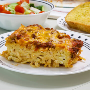 Feature image of one serving of cream cheese spaghetti casserole on a white and black plate.