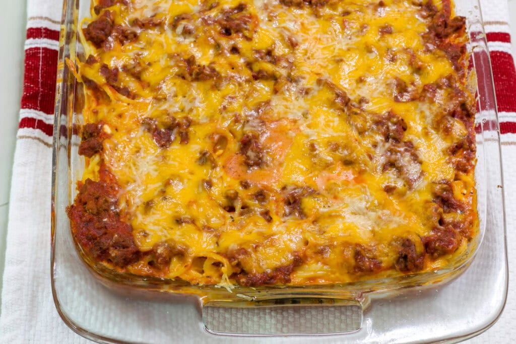 Half of the casserole dish is in frame with the whole uncut baked spaghetti.