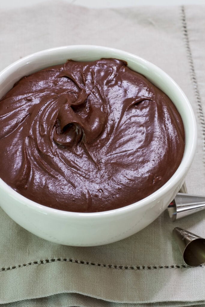 A bowl of mocha frosting on a taupe colored napkin.