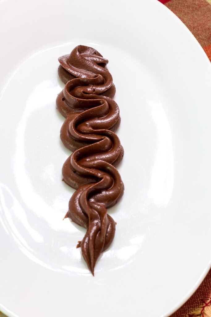 Some piped mocha frosting on a white plate.