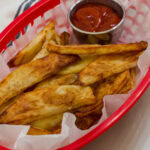 Feature image of the cooked air fryer steak fries and a small bowl of ketchup.