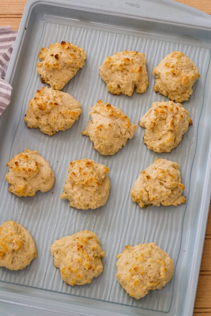 One dozen Light Yogurt Drop Biscuits on a large baking sheet after they were baked.