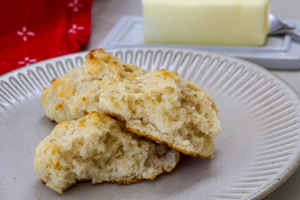 Two biscuits on a plate, one has been split in two so the baked inside is visible.