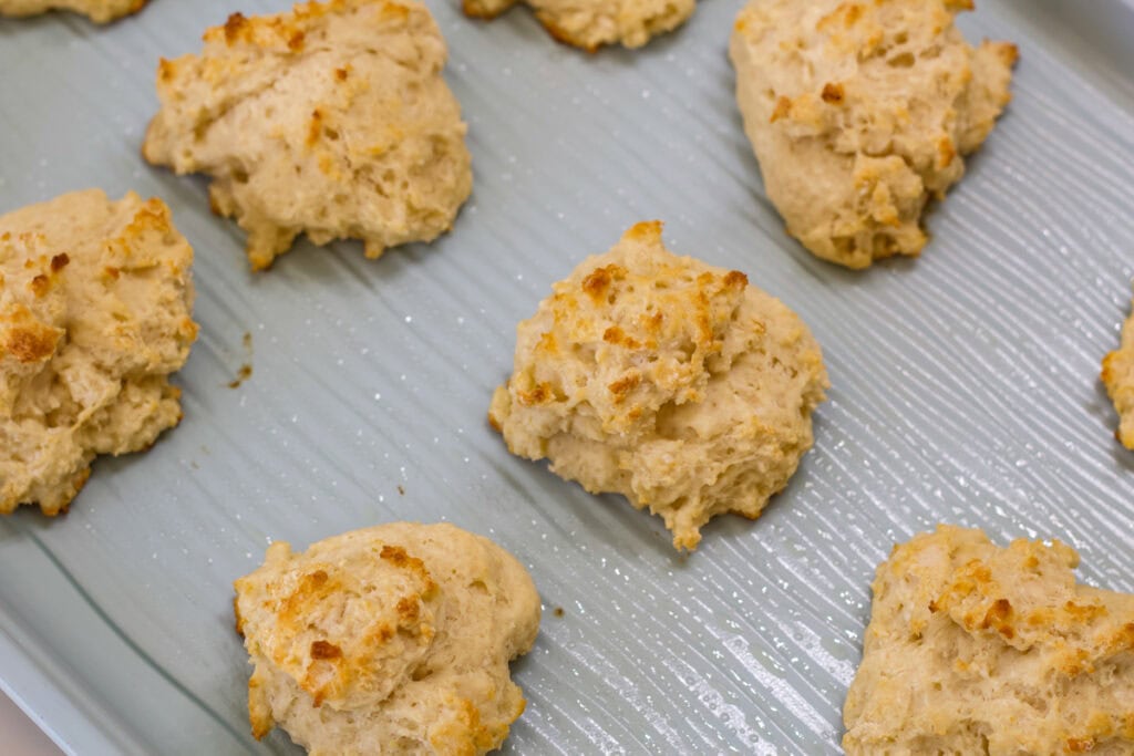 Close up of the sheet pan with baked biscuits on it, only a few biscuits are in the shot.
