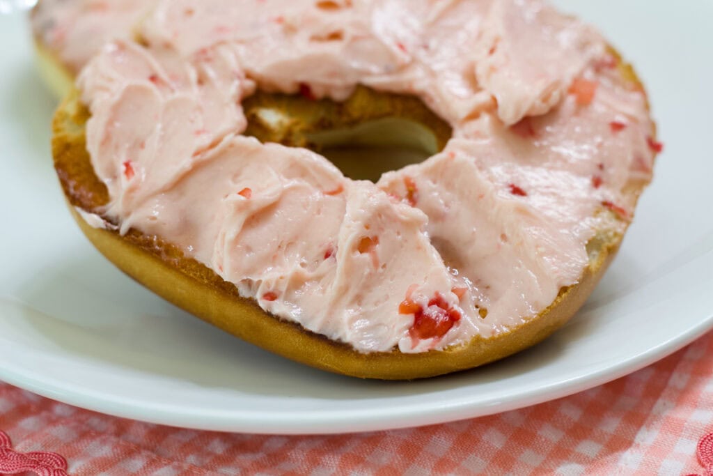 A bagel with Whipped Strawberry Honey Butter spread on it.