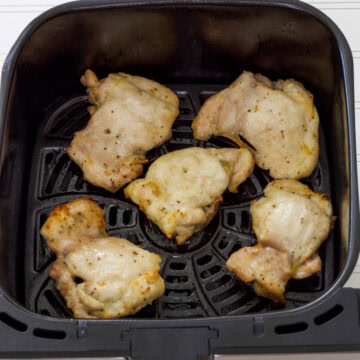 Feature image of five cooked boneless chicken thighs in the air fryer basket.