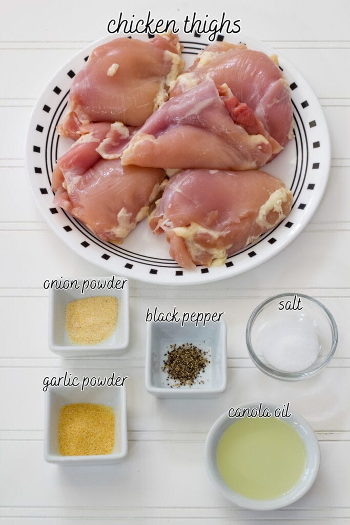 Raw chicken thighs, canola oil, garlic powder, onion powder, salt and black pepper measured out to make the Air Fryer Chicken Thighs.